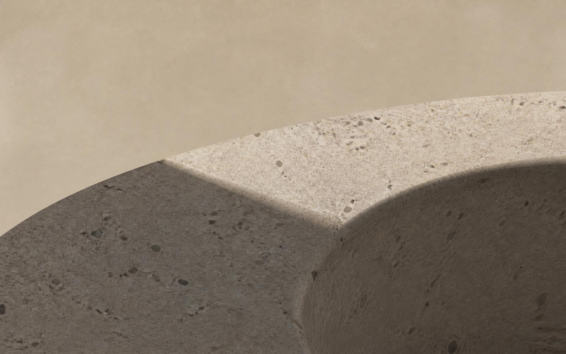 Close-up of a sculptural cast stone surface in warm ivory and charcoal